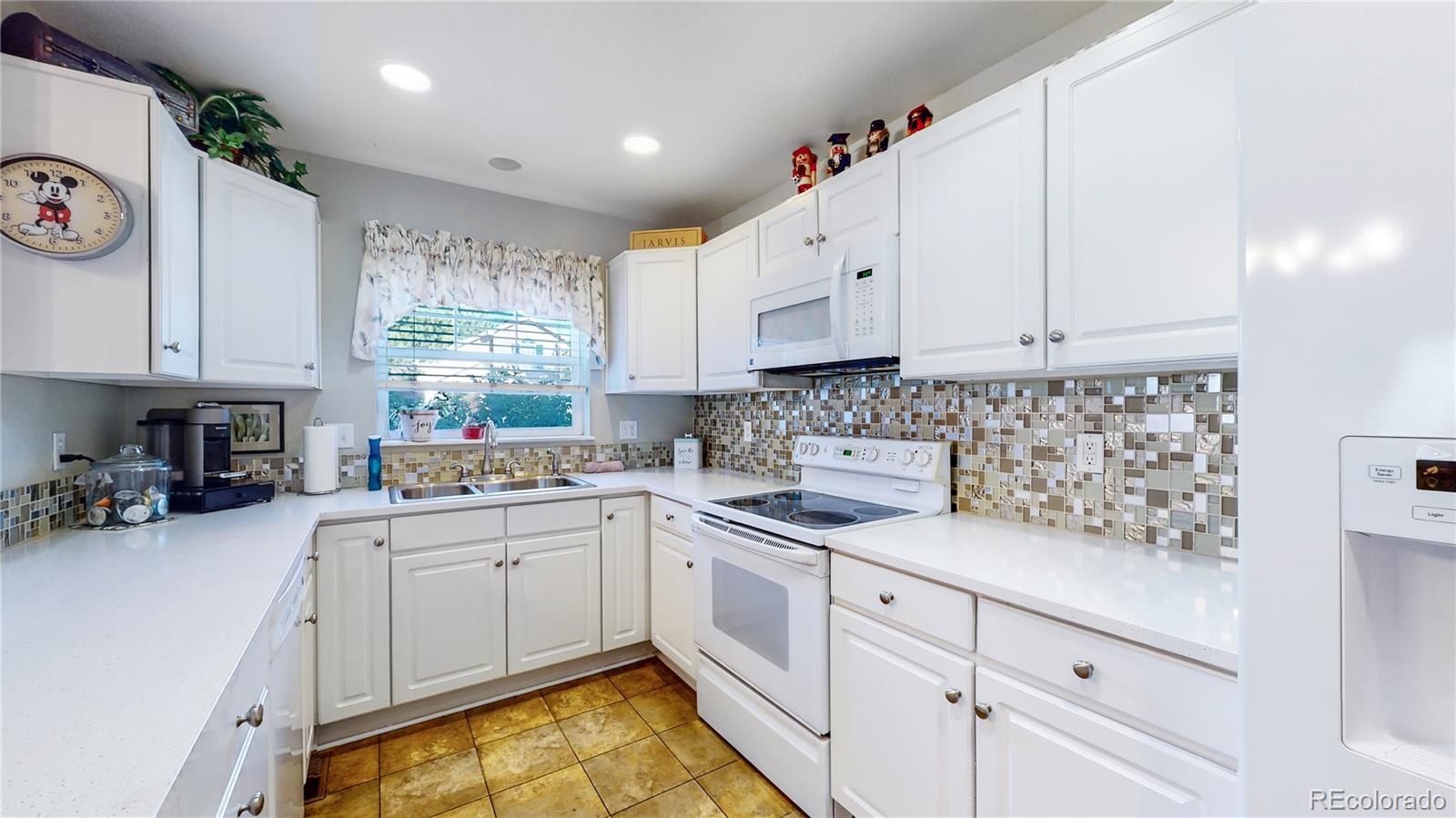 10105 North Grove Loop, Unit A Westminster, CO 80031 - Photo 9 of 40 a kitchen with white cabinets appliances and a window
