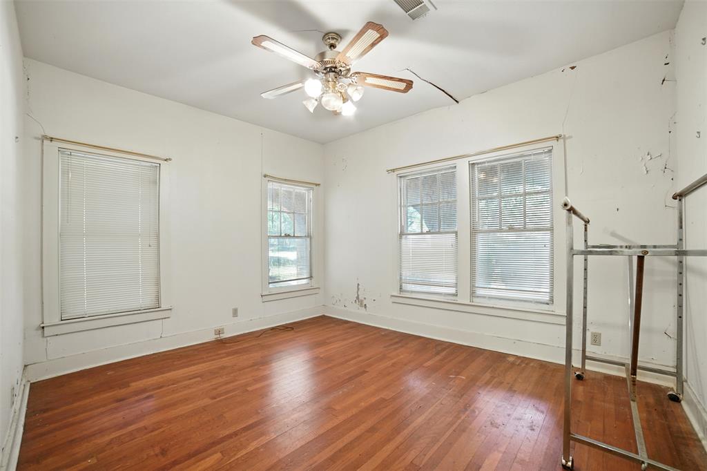 514 South Main Street Lockhart, TX 78644 - Photo 7 of 14 an empty room with wooden floor chandelier fan and windows