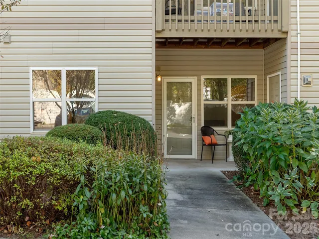 a view of a brick house with plants and a bench