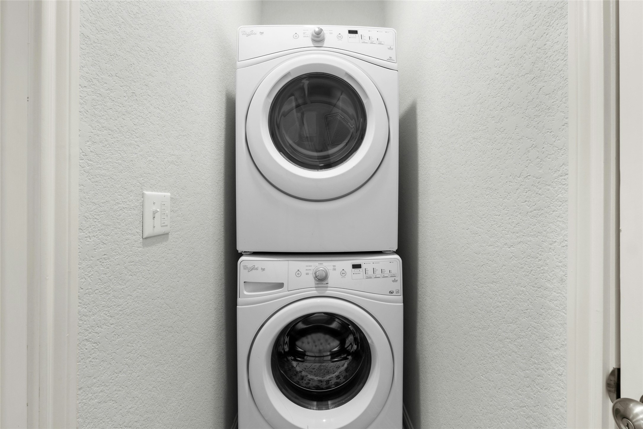 8101 Frida Bend Austin, TX 78744 - Photo 25 of 30 Laundry area featuring stacked washing machine and dryer and a textured wall