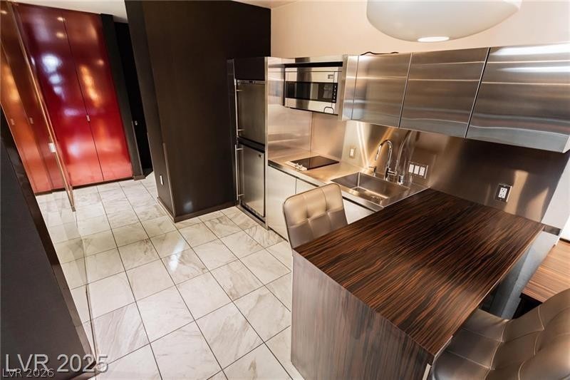 4381 West Flamingo Road, Unit 1809 Las Vegas, NV 89103 - Photo 6 of 11 Kitchen featuring modern cabinets, stainless steel microwave, black electric stovetop, built in refrigerator, and dark countertops