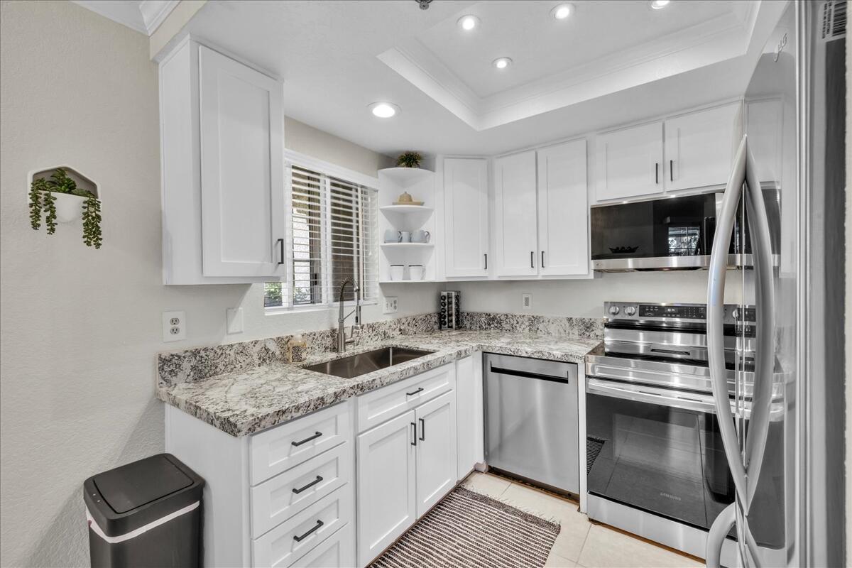 2700 Lawrence Crossley Road, Unit 83 Palm Springs, CA 92264 - Photo 13 of 52 a kitchen with granite countertop a sink stainless steel appliances and white cabinets