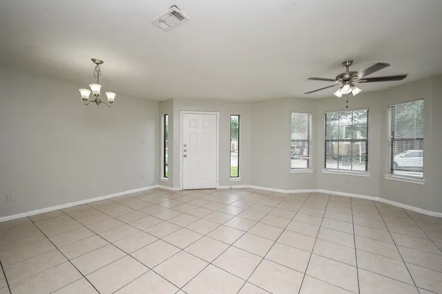 an empty room with windows and chandelier fan