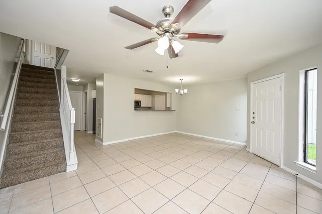 an empty room with white walls and ceiling fan