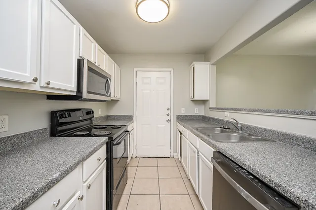 a kitchen with granite countertop a sink a stove and cabinets