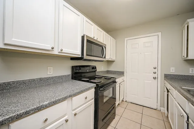a kitchen with stainless steel appliances granite countertop a sink a stove and a microwave oven in a white cabinet