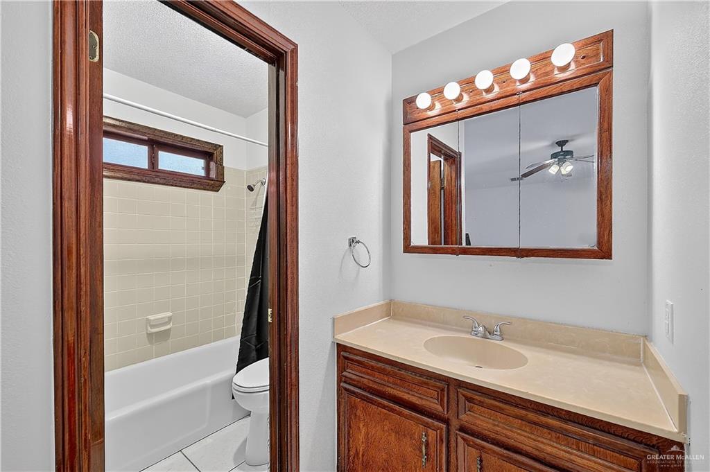 216 West Enfield Road Edinburg, TX 78539 - Photo 17 of 20 Bathroom featuring a vanity with an integrated sink, a framed medicine cabinet, overhead lighting, and a full bathtub with tiled surround