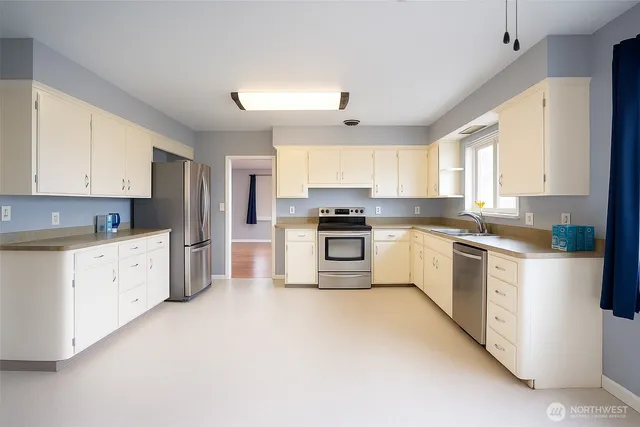 a kitchen with granite countertop white cabinets and stainless steel appliances