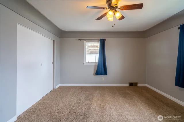 a view of an empty room with window and chandelier fan