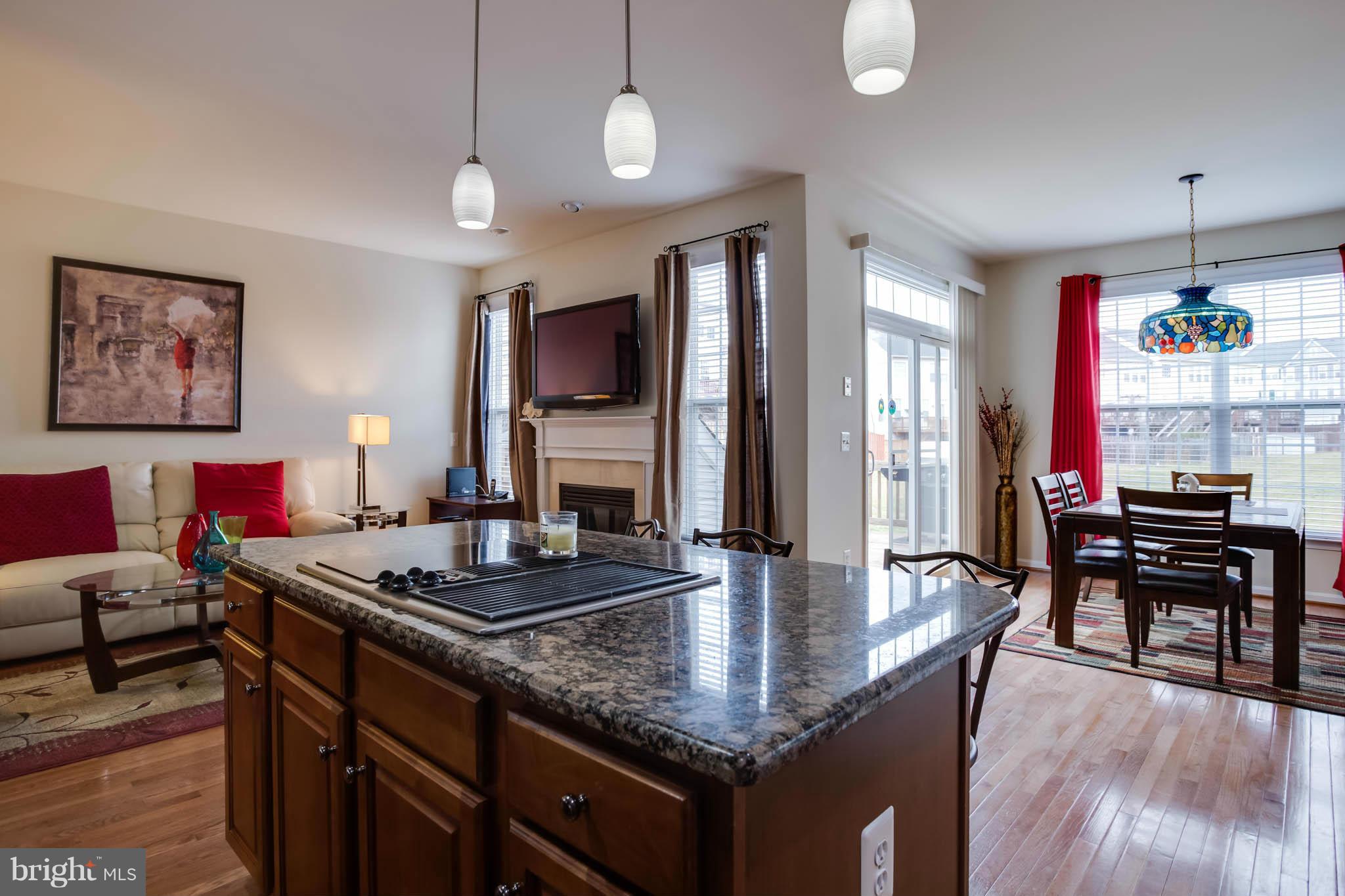 2242 Henry Watts Loop Woodbridge, VA 22191 - Photo 12 of 30 a kitchen with a stove a sink dishwasher a dining table and chairs with wooden floor