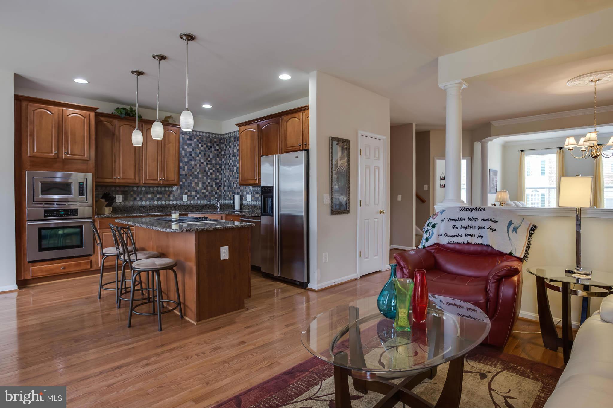 2242 Henry Watts Loop Woodbridge, VA 22191 - Photo 10 of 30 a kitchen with stainless steel appliances kitchen island granite countertop a kitchen island a stove a dining table and chairs