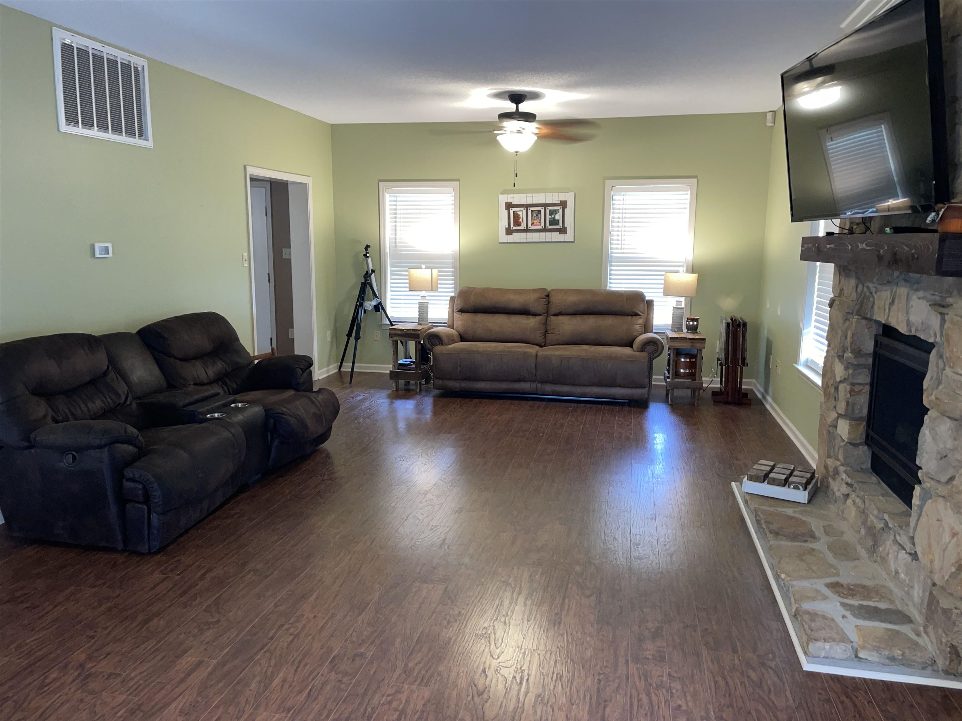 2879 Randolph Road Burlison, TN 38015 - Photo 14 of 29 Living room featuring a stone fireplace, dark hardwood / wood-style flooring, and ceiling fan