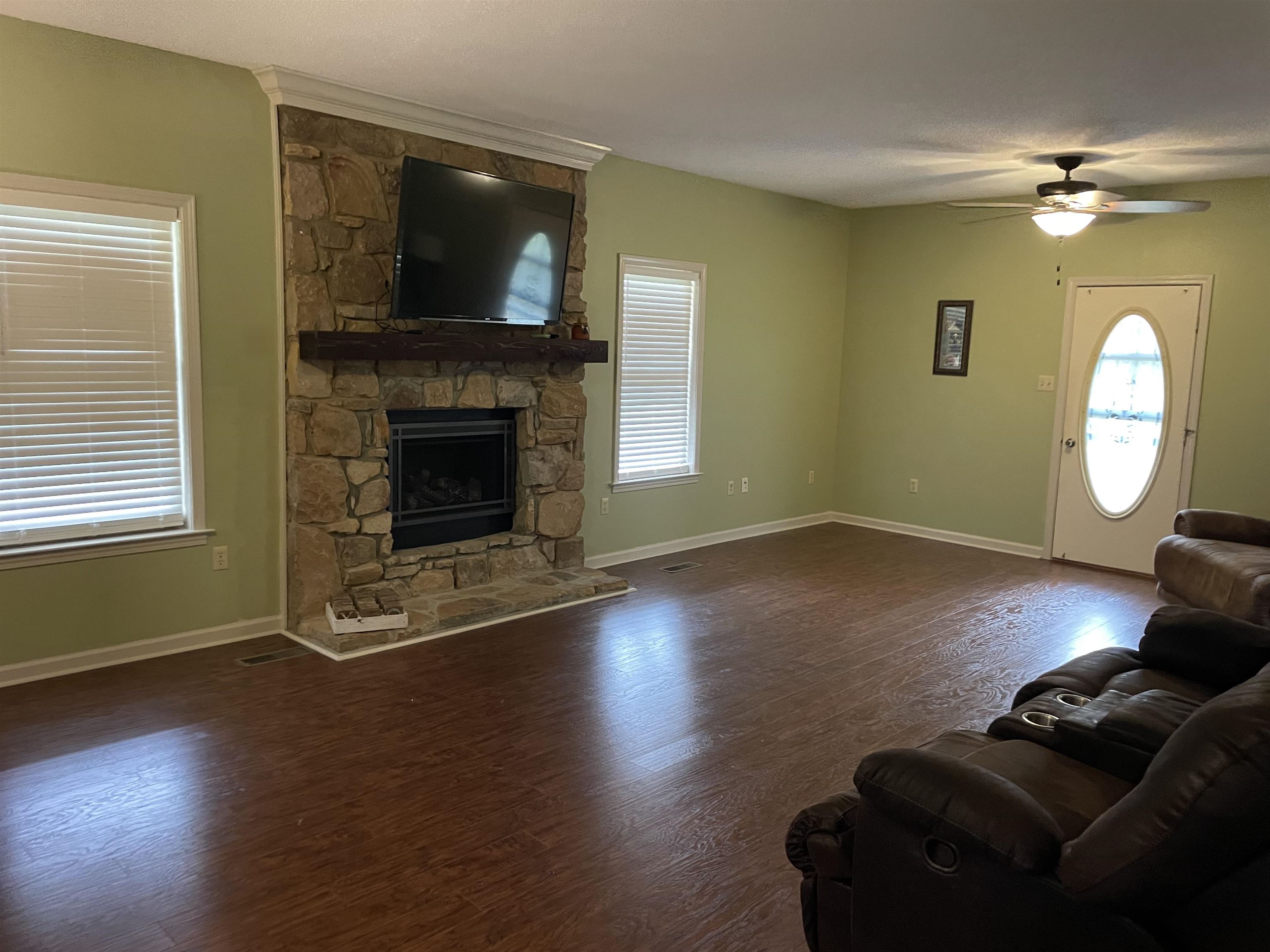 2879 Randolph Road Burlison, TN 38015 - Photo 23 of 29 Unfurnished living room featuring ceiling fan, hardwood / wood-style flooring, and a stone fireplace