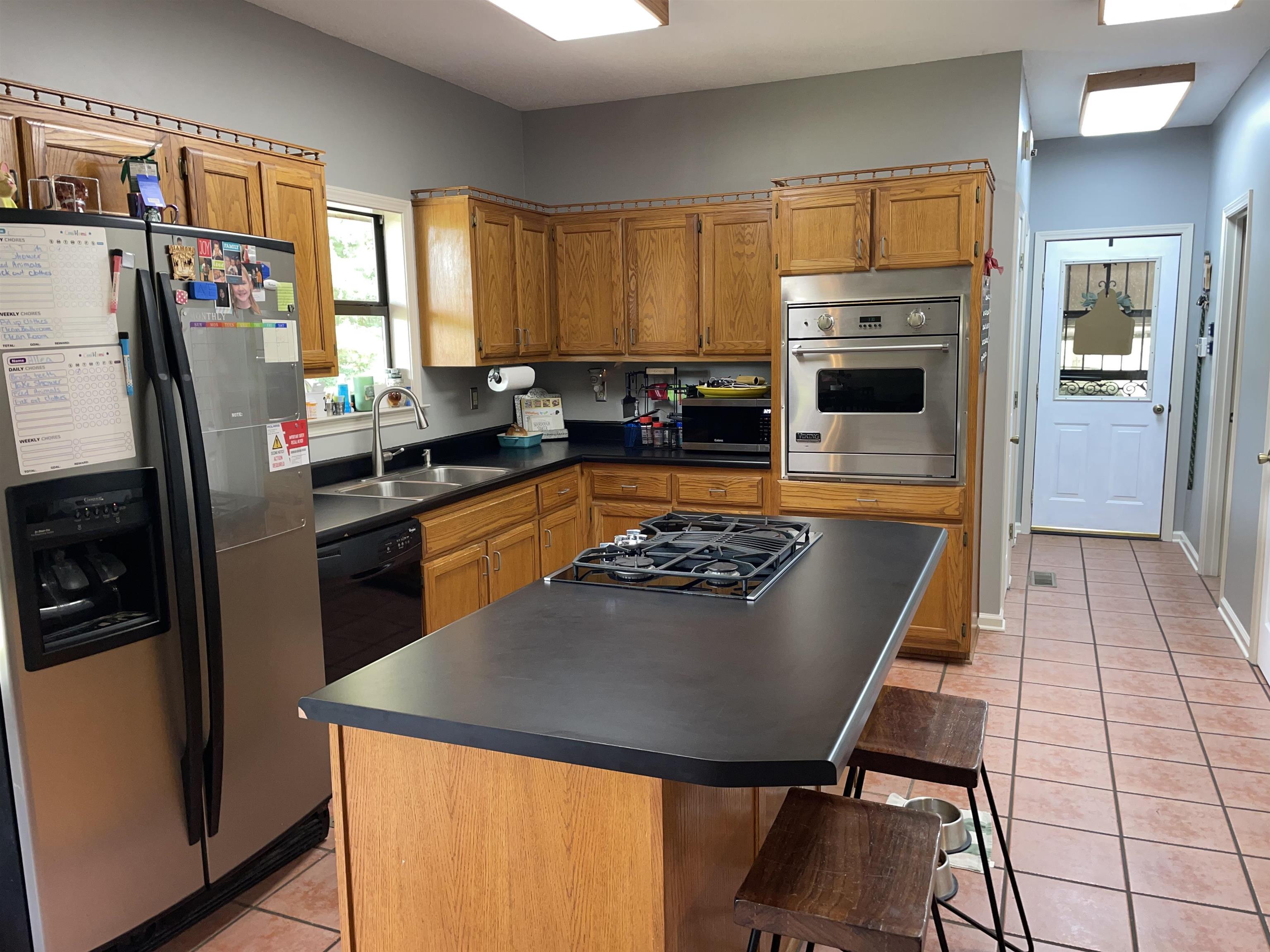 2879 Randolph Road Burlison, TN 38015 - Photo 29 of 29 Kitchen with a kitchen bar, black appliances, light tile patterned floors, a center island, and sink