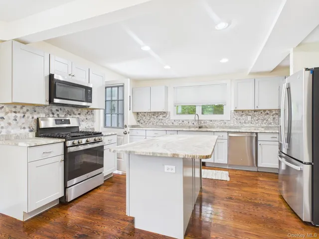 a kitchen with stainless steel appliances granite countertop a stove top oven a sink dishwasher and a refrigerator