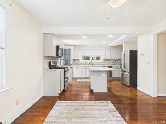 a white kitchen with wooden floor and stainless steel appliances