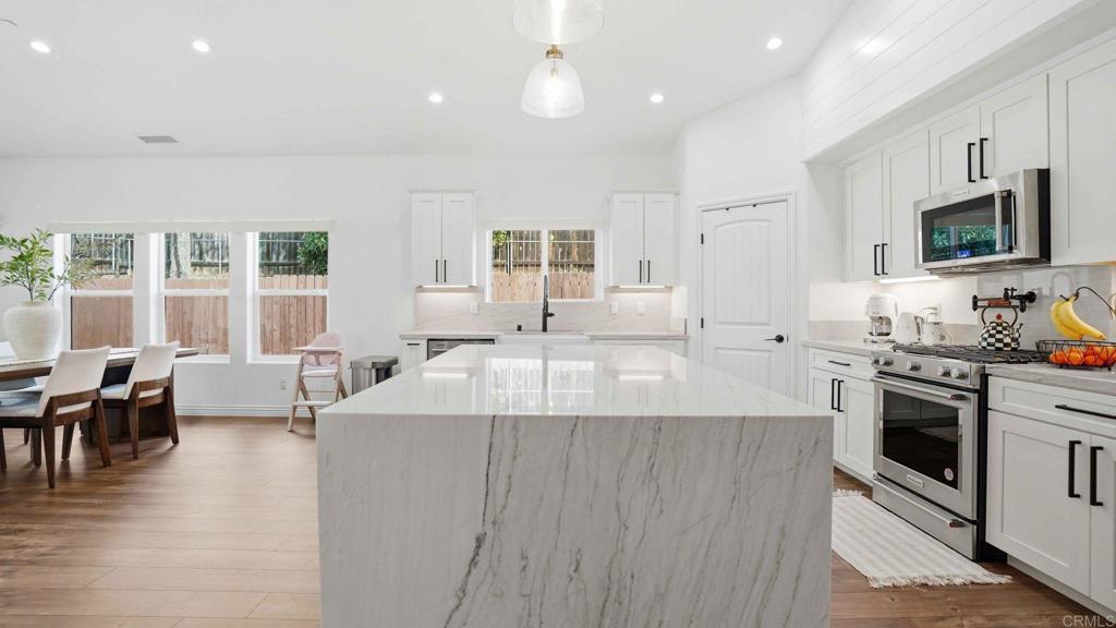9391 Los Coches Road Lakeside, CA 92040 - Photo 19 of 65 a large kitchen with stainless steel appliances a large counter top a stove a sink a dining table and chairs