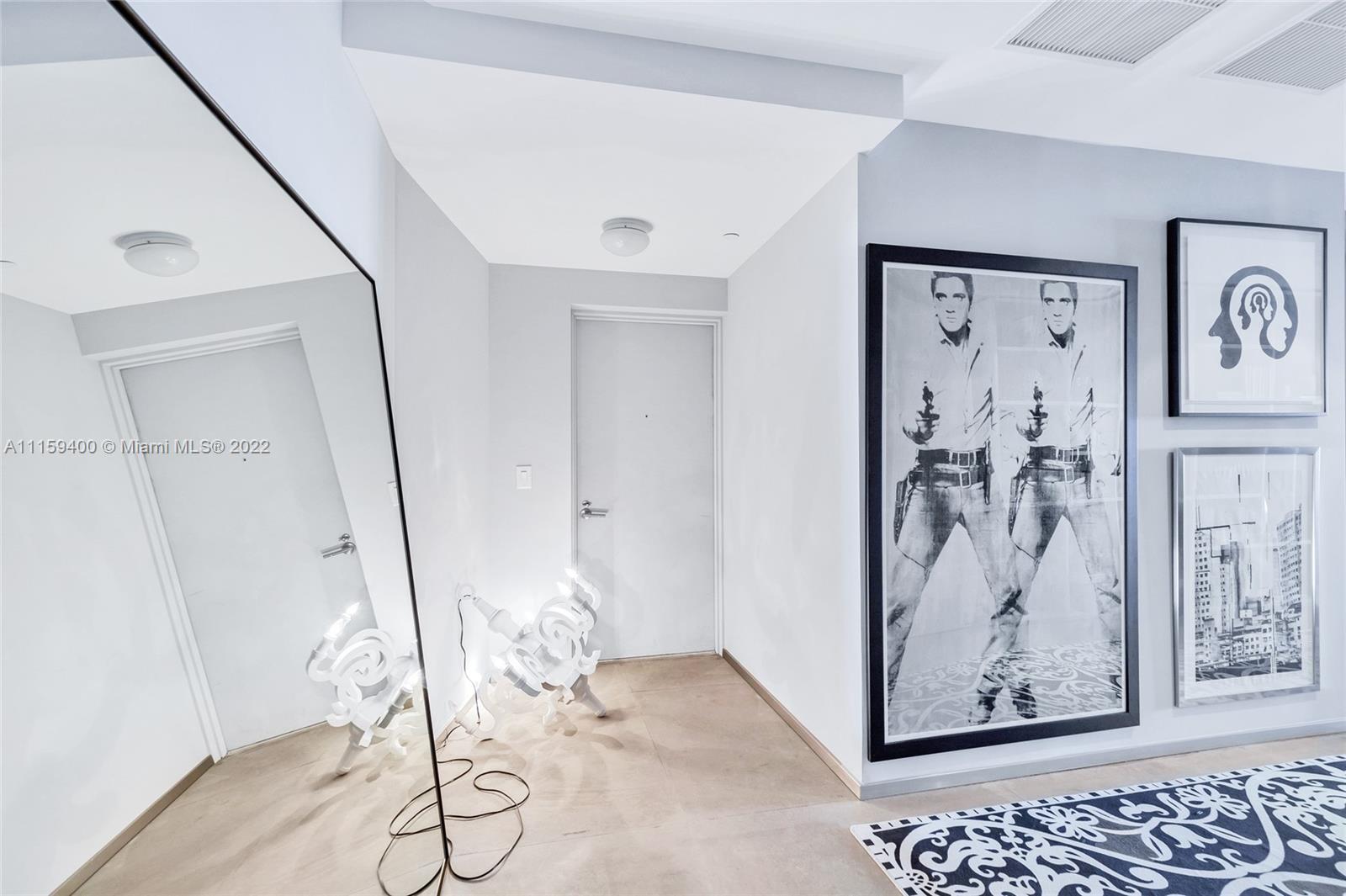 1100 Biscayne Boulevard, Unit 1801 Miami, FL 33132 - Photo 25 of 27 a view of a hallway with paintings on the wall and glass door