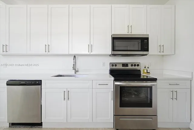 a kitchen with white cabinets and stainless steel appliances