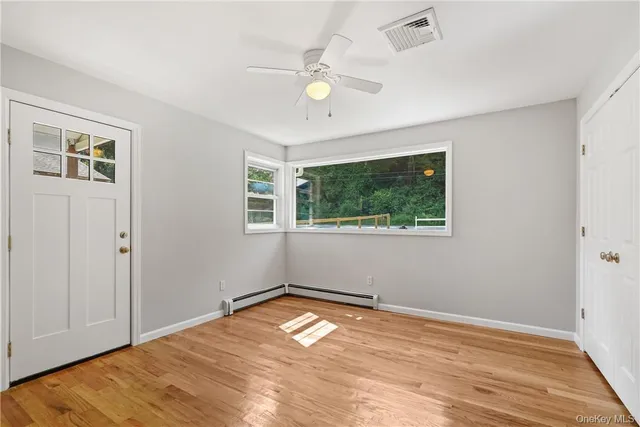 a view of empty room with wooden floor and fan