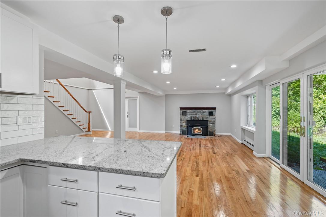 448 Sprout Brook Road Garrison, NY 10524 - Photo 2 of 22 Kitchen with backsplash, white cabinets, light stone counters, and light wood-type flooring