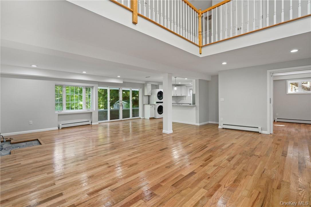 448 Sprout Brook Road Garrison, NY 10524 - Photo 5 of 22 Unfurnished living room featuring stacked washing maching and dryer, light hardwood / wood-style flooring, and baseboard heating