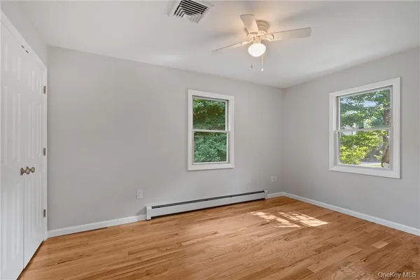 a view of empty room with wooden floor and fan