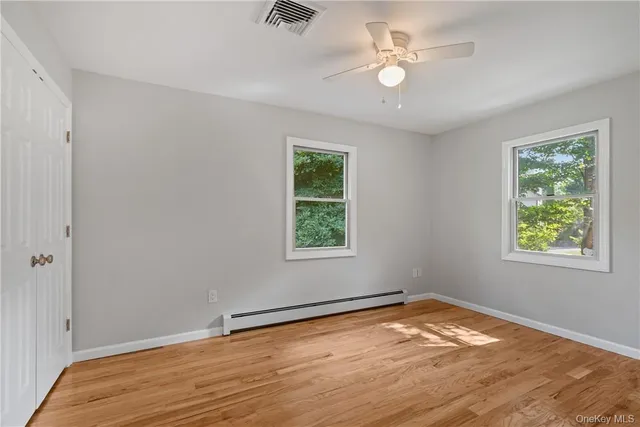 a view of empty room with wooden floor and fan