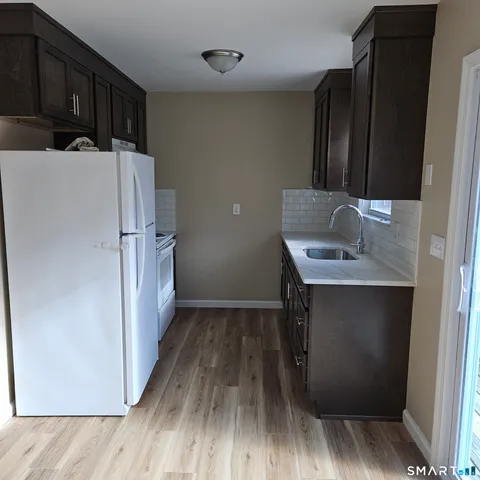 a kitchen with a sink a refrigerator and wooden floor