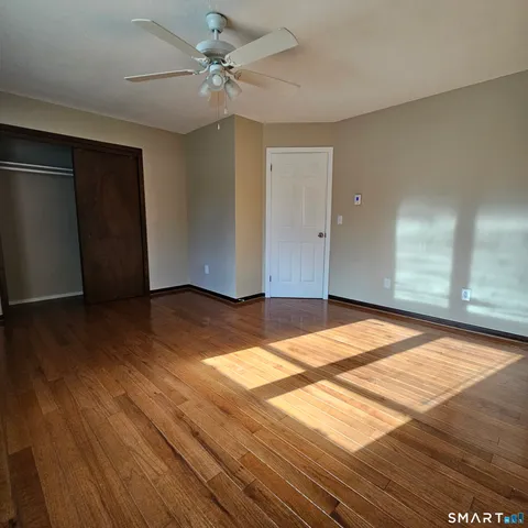 a view of empty room with wooden floor and fan