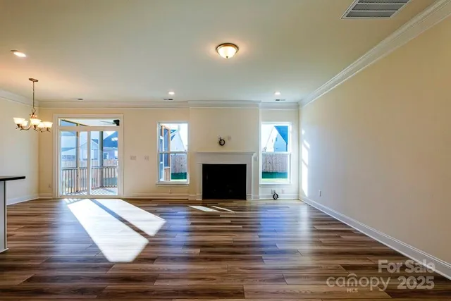 an empty room with wooden floor fireplace and windows