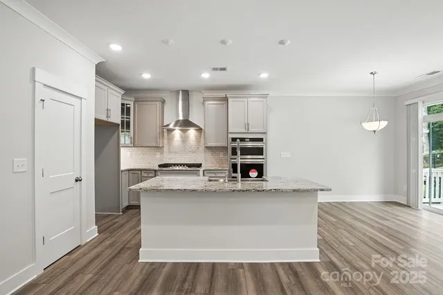 a large white kitchen with kitchen island a sink stainless steel appliances and cabinets