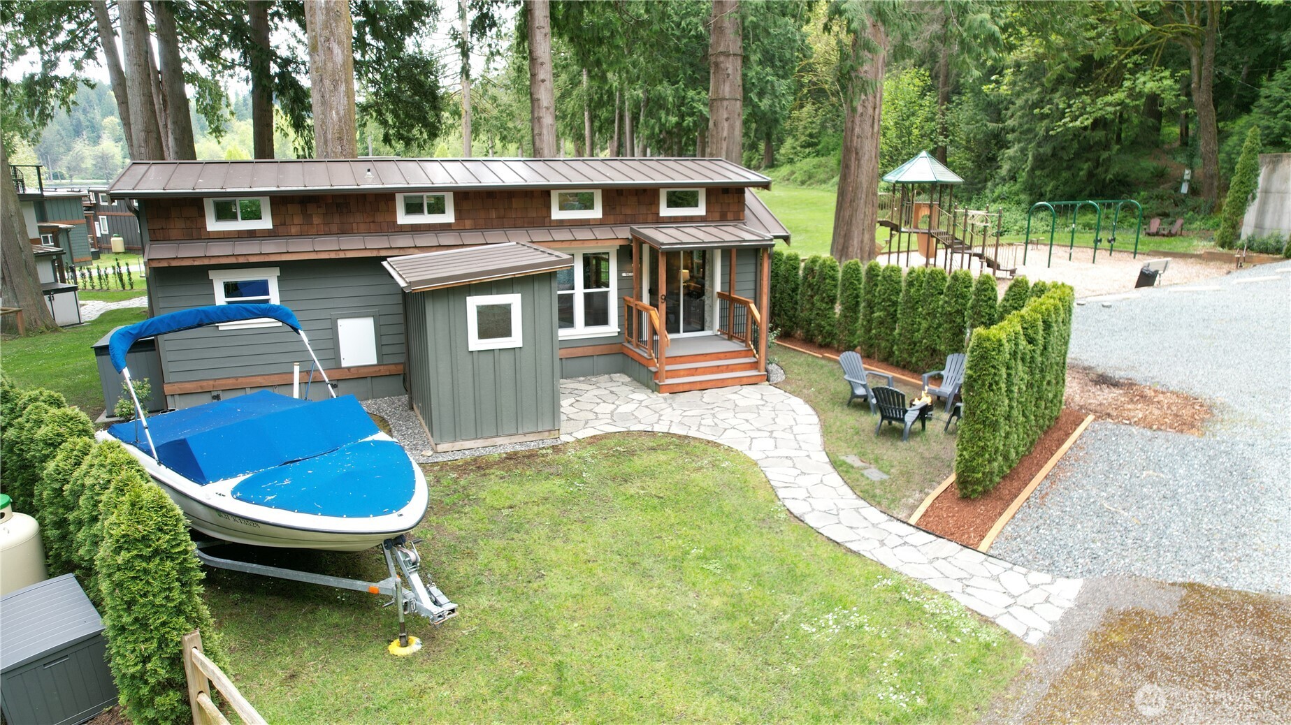a view of a backyard with table and chairs potted plants and large tree