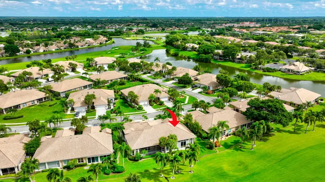 a view of a white house with a big yard and potted plants