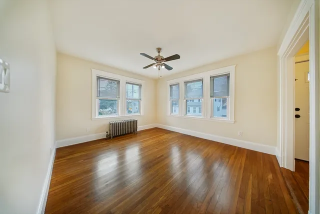 an empty room with wooden floor chandelier and windows