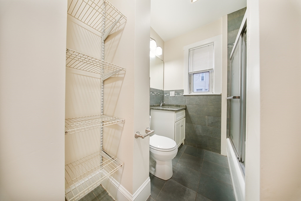 39 McDonald Street, Unit 39 Quincy, MA 02169 - Photo 7 of 15 a bathroom with a granite countertop toilet sink and a mirror