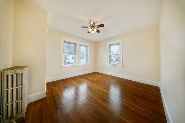 a view of empty room with wooden floor and fan
