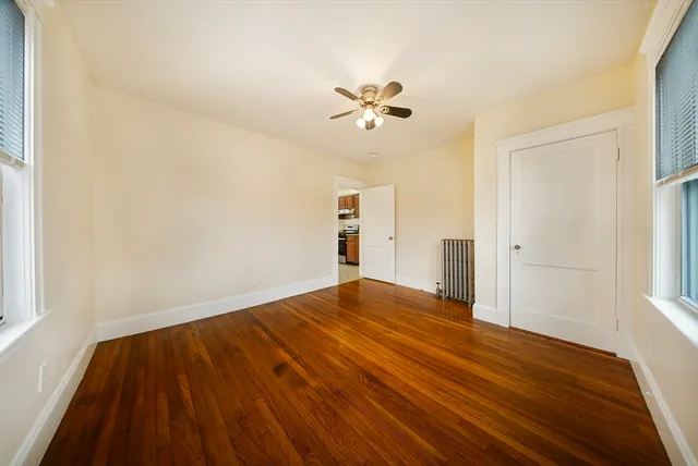 a view of empty room with wooden floor and fan