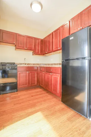 a kitchen with stainless steel appliances granite countertop a refrigerator a stove and a sink with wooden cabinets