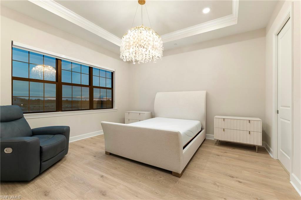 15328 Lucerna Street, Unit 202 Naples, FL 34114 - Photo 16 of 32 a room with a bed and a chandelier