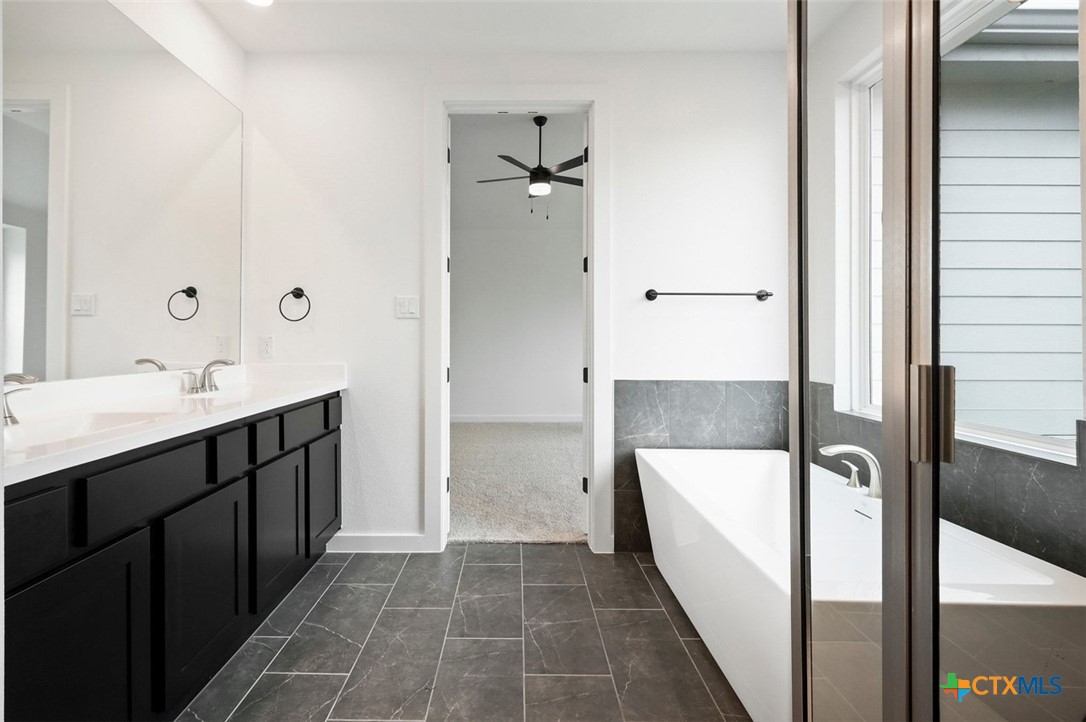 12213 Moon Pool Schertz, TX 78154 - Photo 14 of 25 a bathroom with a double vanity sink a mirror and a bathtub