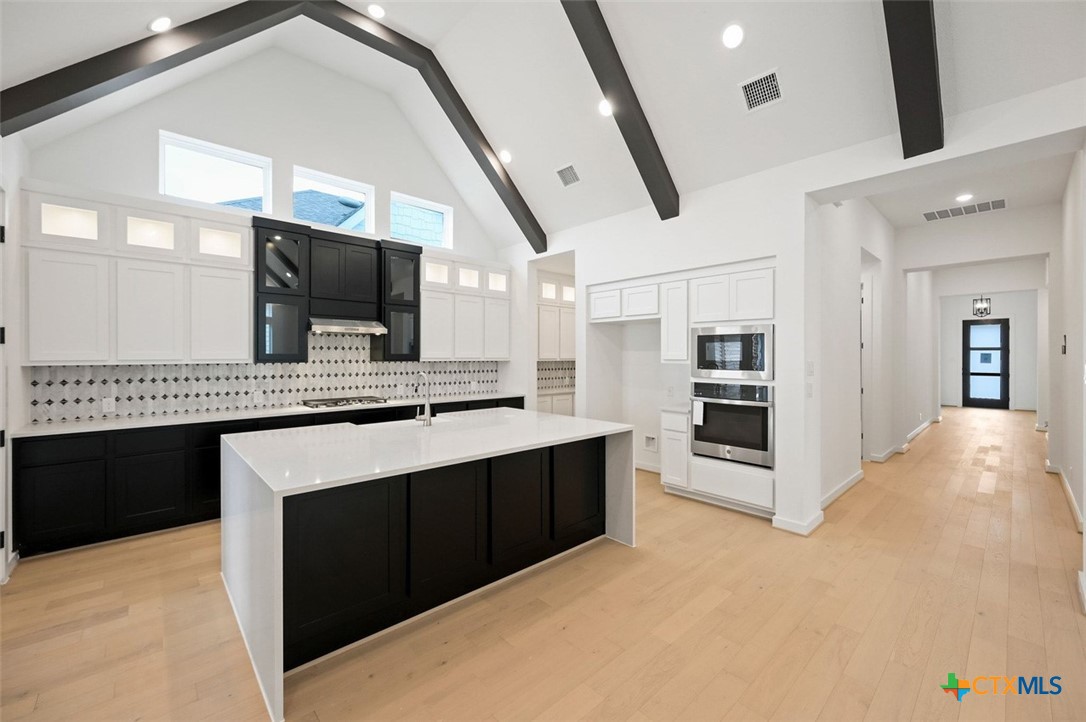 12213 Moon Pool Schertz, TX 78154 - Photo 7 of 25 a large white kitchen with stainless steel appliances kitchen island granite countertop a refrigerator and microwave