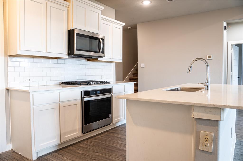 348 Braves Way Lavon, TX 75166 - Photo 7 of 29 a kitchen with stainless steel appliances a stove microwave and sink