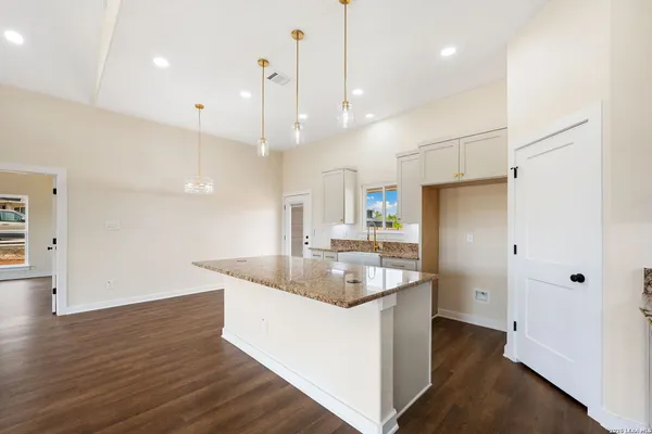 a kitchen with stainless steel appliances granite countertop a sink a refrigerator and a wooden floor
