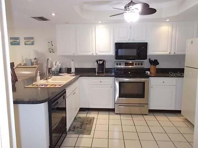 14001 Gulf Boulevard, Unit 407 Madeira Beach, FL 33708 - Photo 7 of 39 a kitchen with a sink a stove and cabinets