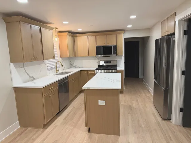 a kitchen with stainless steel appliances a stove top oven a refrigerator a sink and dishwasher with wooden floor