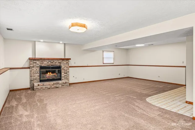 a view of an empty room with a fireplace and a window