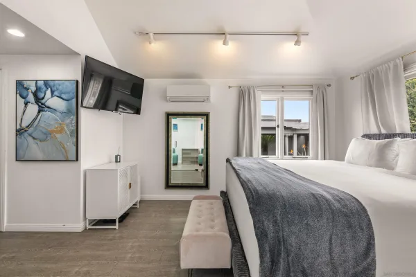 a spacious bedroom with a bed and a flat tv screen on the dresser