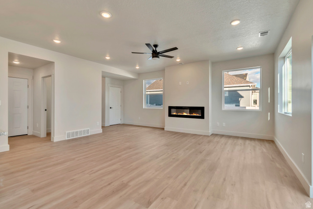 2535 West Santa Fe Drive Mapleton, UT 84664 - Photo 8 of 26 Unfurnished living room featuring a glass covered fireplace, ceiling fan, light wood-style flooring, and recessed lighting