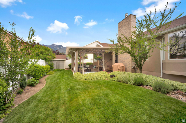 2139 Village Point Way Sandy, UT 84093 - Photo 31 of 35 Private backyard featuring a lush lawn, mature landscaping, a covered patio structure, and water feature.